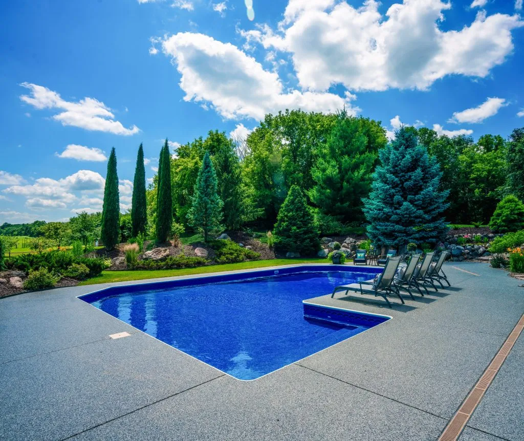 an outdoor swimming pool featuring a decorative concrete or polyurea deck coating for enhanced durability and safety.