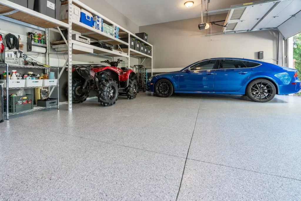 blue car and atv parked in garage with fresh concrete coating floor that is better than epoxy floors