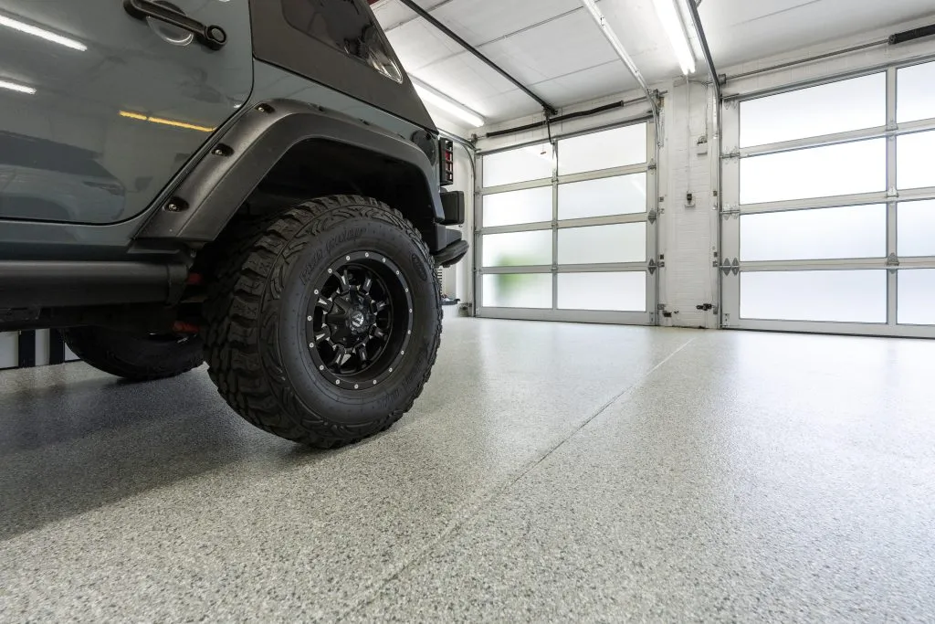 a modern garage featuring a durable concrete floor coating, likely epoxy or polyurea, designed to protect against chemical spills and heavy traffic.