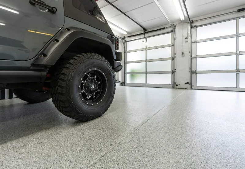 a modern garage featuring a durable concrete floor coating, likely epoxy or polyurea, designed to protect against chemical spills and heavy traffic.