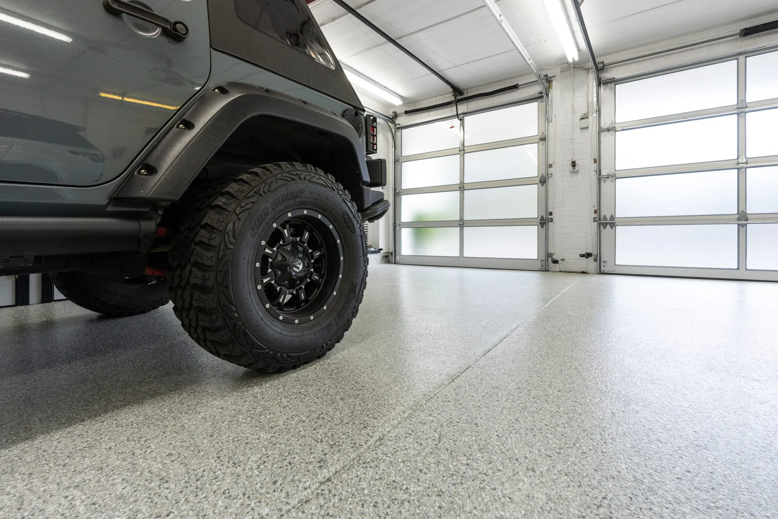a modern garage featuring a durable concrete floor coating, likely epoxy or polyurea, designed to protect against chemical spills and heavy traffic.