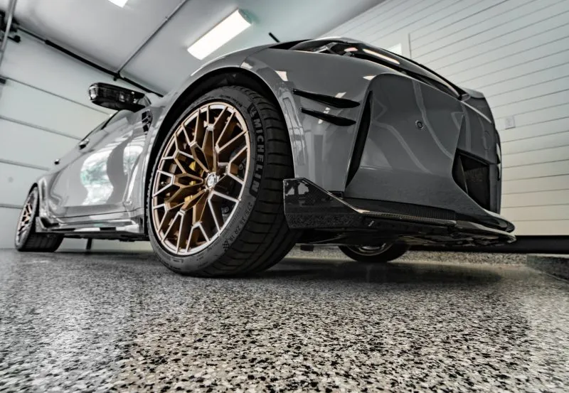 a modern sports car, specifically a BMW X3M, equipped with custom alloy wheels and a distinctive matte grey wrap.