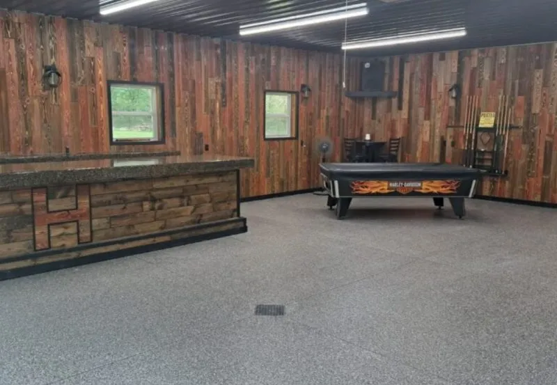 a finished room, possibly a workshop, garage, or finished basement, featuring wood-paneled walls, epoxy flooring, and a pool table.