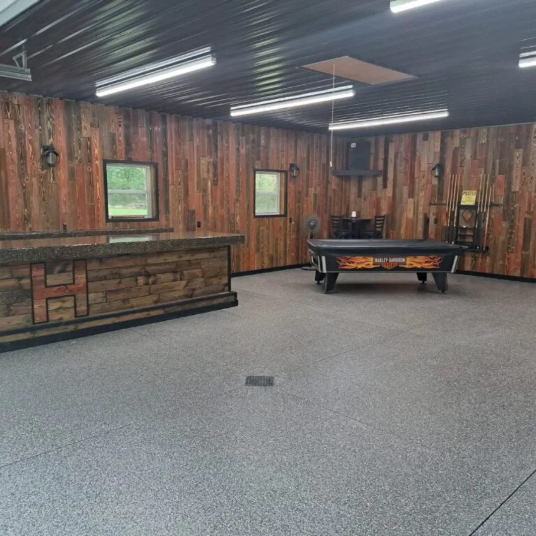 a finished room, possibly a workshop, garage, or finished basement, featuring wood-paneled walls, epoxy flooring, and a pool table.