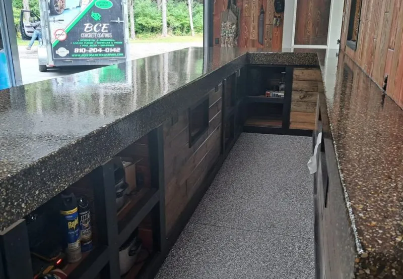 a custom-built bar or counter area, likely for outdoor entertaining or a shed, featuring stone countertops and wooden walls.
