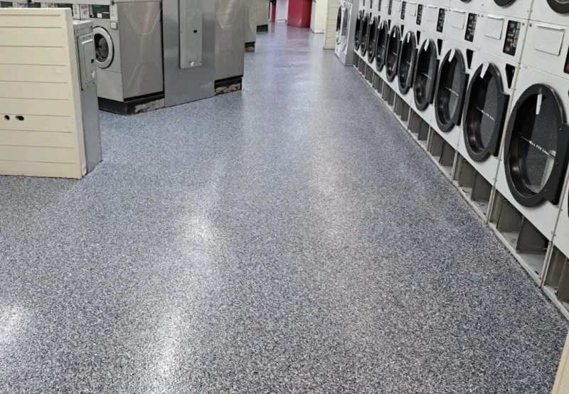 a commercial laundromat featuring durable, seamless polyurea or epoxy floor coating with a decorative flake finish.