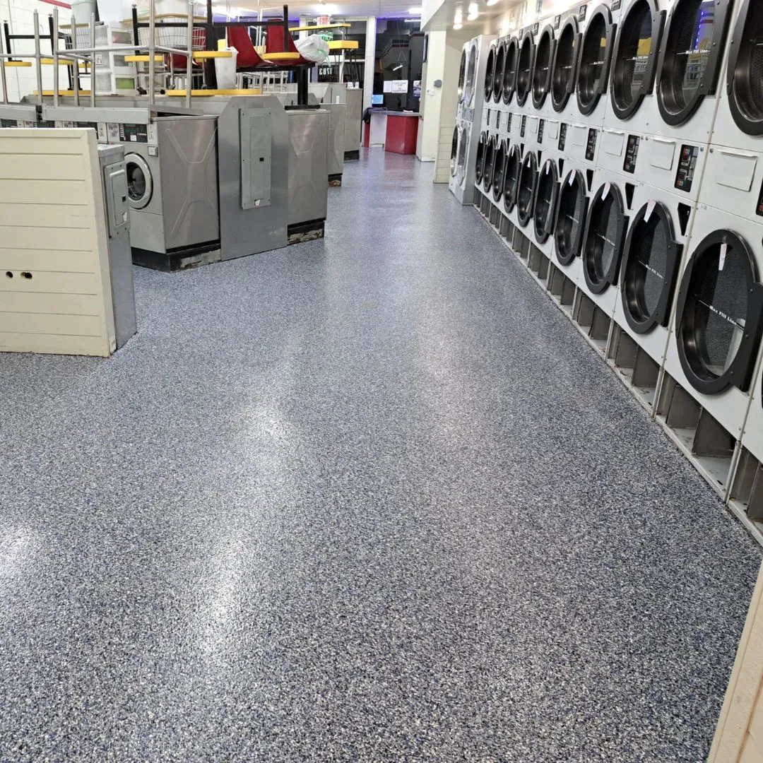 a commercial laundromat featuring durable, seamless polyurea or epoxy floor coating with a decorative flake finish.
