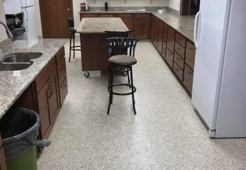a residential kitchen featuring a central island with bar stool seating and epoxy-coated flooring.