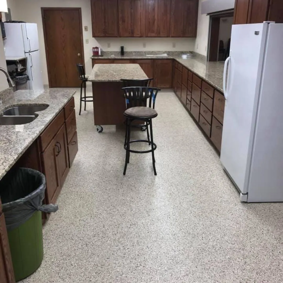 a residential kitchen featuring a central island with bar stool seating and epoxy-coated flooring.